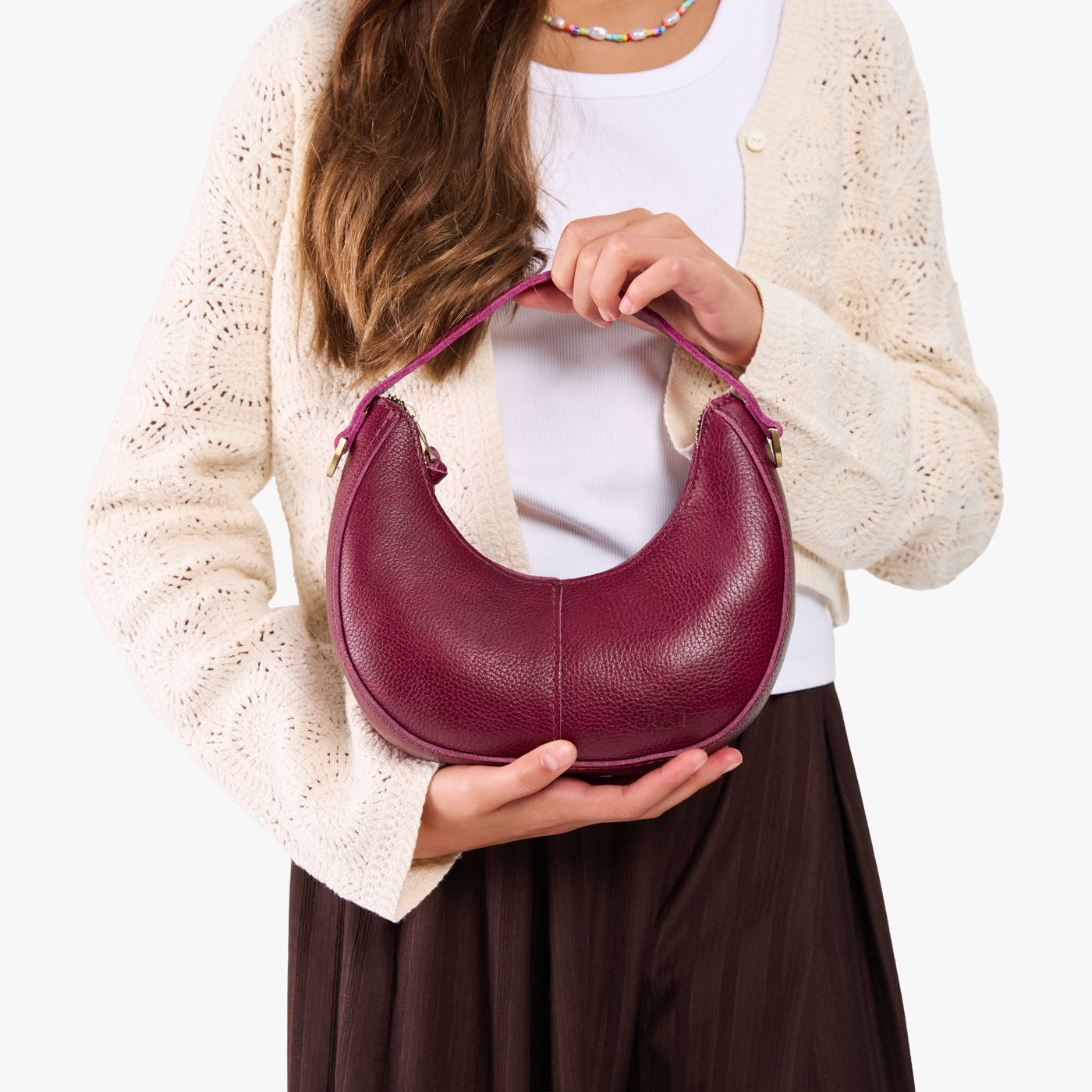 Orchid | Model with a crescent shaped shoulder bag with zipper closure and gold accents