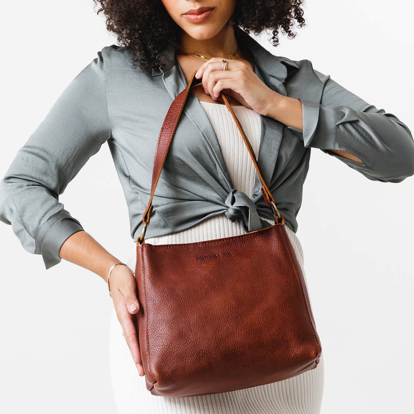 Nutmeg*Classic | Model carrying leather triangular shoulder bag with zipper top closure and wide shoulder strap