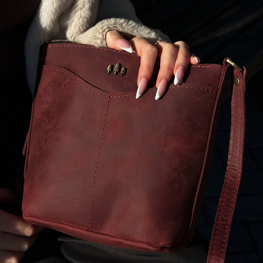 Red leather handbag held by a person with a dark background