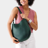 Forest Green Large | Woman wearing rounded shoulder bag with adjustable strap on a white background