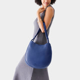 Molino Blue Large | Woman wearing rounded shoulder bag with adjustable strap on a white background