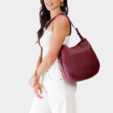 Orchid Large | Woman wearing rounded shoulder bag with adjustable strap on a white background