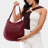 Orchid Large | Woman wearing rounded shoulder bag with adjustable strap on a white background