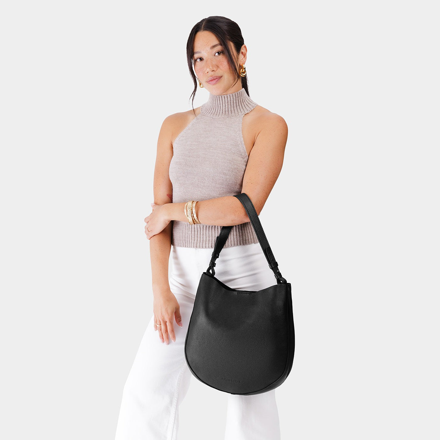 Pebbled--black*Large | Woman wearing rounded shoulder bag with adjustable strap on a white background