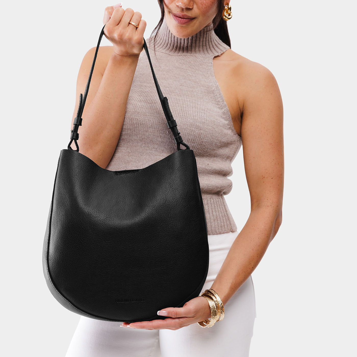 Pebbled--black*Large | Woman wearing rounded shoulder bag with adjustable strap on a white background