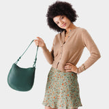 Forest Green Medium | Woman wearing rounded shoulder bag with adjustable strap on a white background