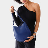 Molino Blue Medium | Woman wearing rounded shoulder bag with adjustable strap on a white background