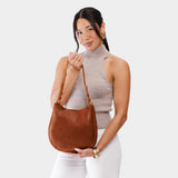 Nutmeg Medium | Woman wearing rounded shoulder bag with adjustable strap on a white background
