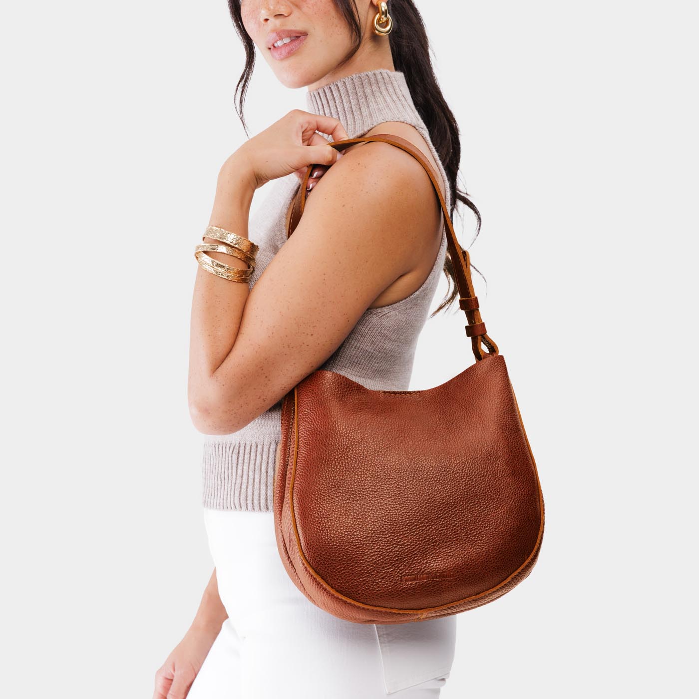 Nutmeg*Medium | Woman wearing rounded shoulder bag with adjustable strap on a white background