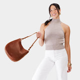 Nutmeg Medium | Woman wearing rounded shoulder bag with adjustable strap on a white background