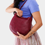 Orchid Medium | Woman wearing rounded shoulder bag with adjustable strap on a white background