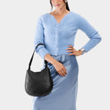 Pebbled--black Medium | Woman wearing rounded shoulder bag with adjustable strap on a white background