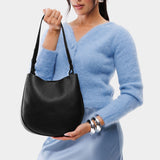 Pebbled--black Medium | Woman wearing rounded shoulder bag with adjustable strap on a white background