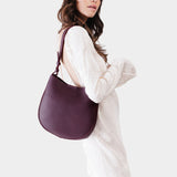 Plum Medium | Woman wearing rounded shoulder bag with adjustable strap on a white background