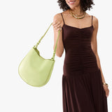 Shadow Lime Medium | Model carrying round leather purse with adjustable shoulder strap