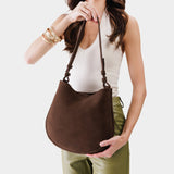 Stagecoach Medium | Woman wearing rounded shoulder bag with adjustable strap on a white background