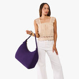 Imperial Oversized | Model holding u-shaped, flat-bottomed leather shoulder bag with adjustable strap