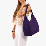 Imperial Oversized | Model holding u-shaped, flat-bottomed leather shoulder bag with adjustable strap