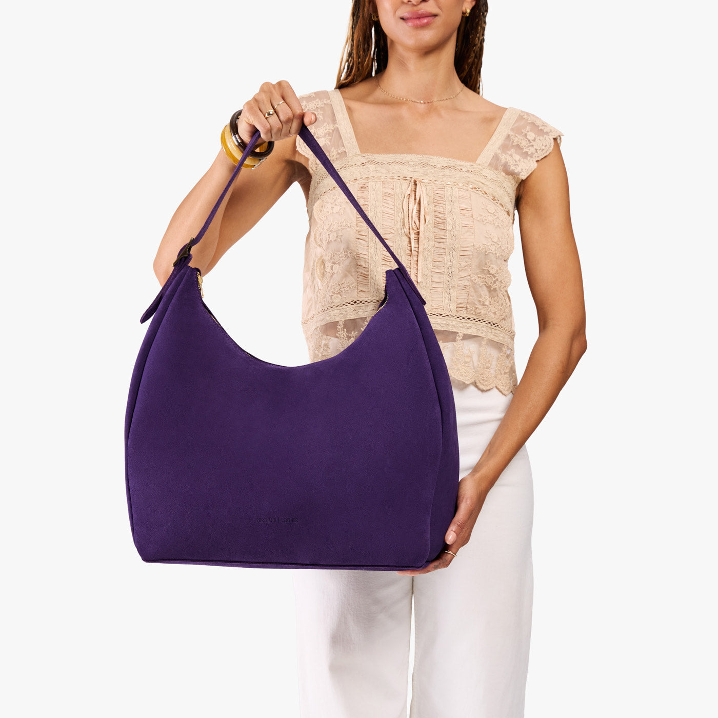 Imperial*Oversized | Model holding u-shaped, flat-bottomed leather shoulder bag with adjustable strap