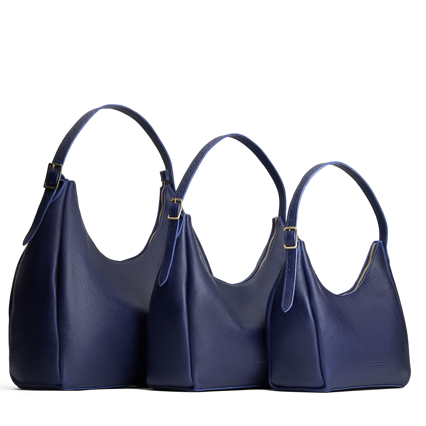 Cobalt | Size comparison image of oversized, large, and medium u-shaped, flat-bottomed leather shoulder bags with adjustable strap