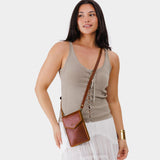 Nutmeg | Model wearing slim, phone-shaped crossbody purse with magnetic closure