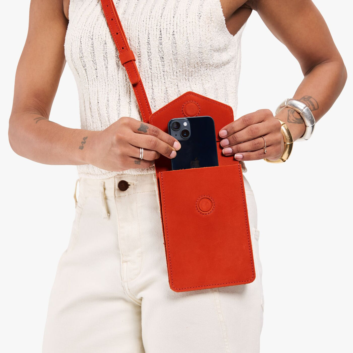 Paprika | Model pulling a smartphone out of slim, phone-shaped crossbody purse with magnetic closure
