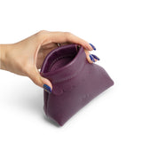 Plum | Hand holding leather coin pouch with scalloped edge and three Portland leather tree emblems open