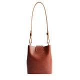 Chestnut | Leather bucket shoulder bag with adjustable strap and magnetic closure on a white background