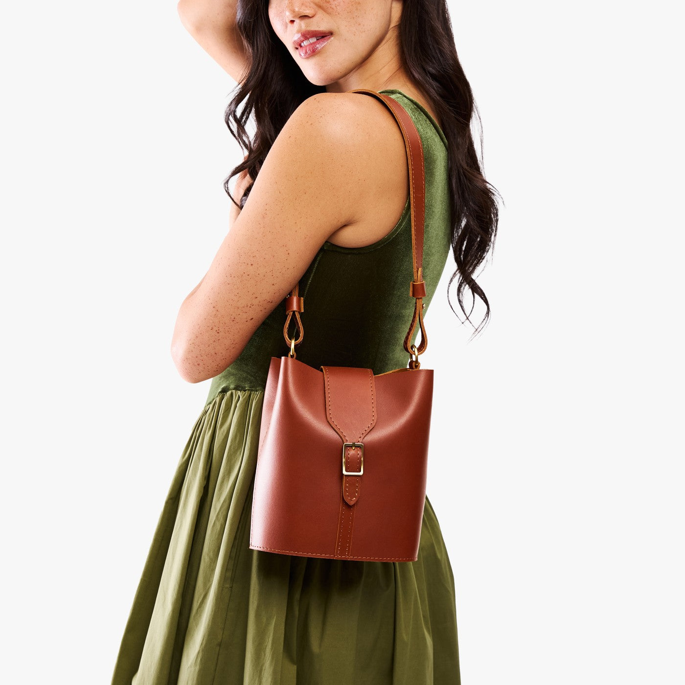 Chestnut | Model wearing leather bucket shoulder bag with adjustable strap and magnetic closure 