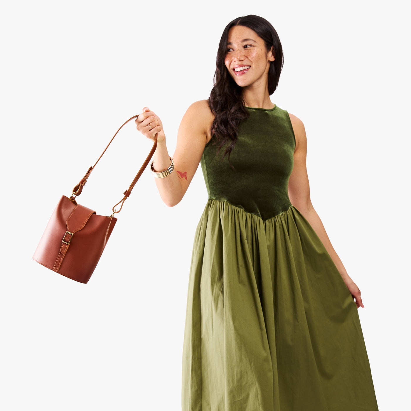 Chestnut | Model wearing leather bucket shoulder bag with adjustable strap and magnetic closure 