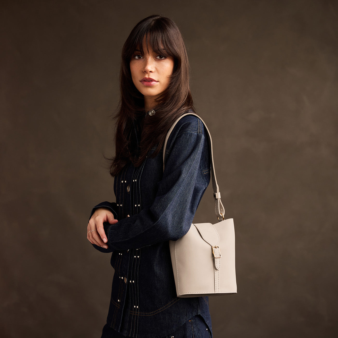 Dragon Bone | Model wearing leather bucket shoulder bag with adjustable strap and magnetic closure 