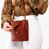 Nutmeg | Model wearing leather bucket shoulder bag with adjustable strap and magnetic closure 
