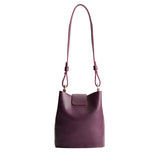 Plum | Leather bucket shoulder bag with adjustable strap and magnetic closure on a white background