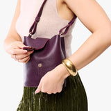 Plum | Model wearing leather bucket shoulder bag with adjustable strap and magnetic closure 