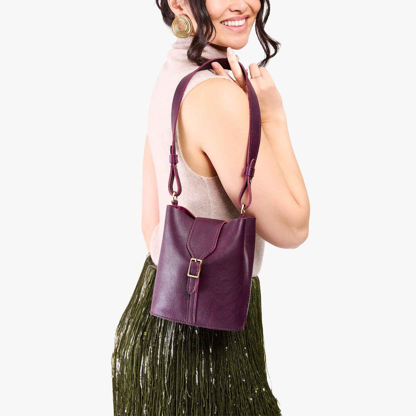 Plum | Model wearing leather bucket shoulder bag with adjustable strap and magnetic closure 