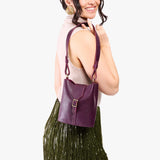 Plum | Model wearing leather bucket shoulder bag with adjustable strap and magnetic closure 