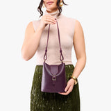 Plum | Model wearing leather bucket shoulder bag with adjustable strap and magnetic closure 