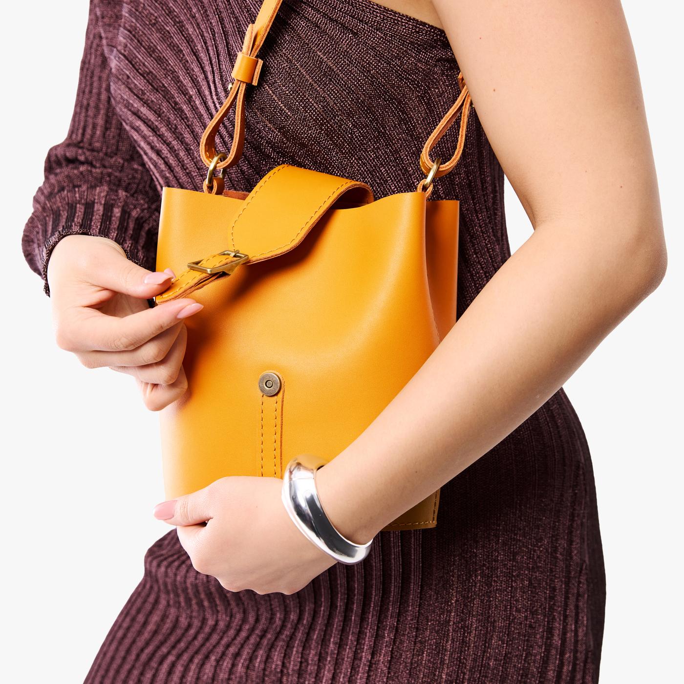 Sunflower | Model wearing leather bucket shoulder bag with adjustable strap and magnetic closure 
