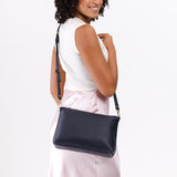Night Owl Large | A Model holding a zip top crossbody bag with detachable strap