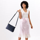 Night Owl Large | A Model holding a zip top crossbody bag with detachable strap