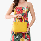Canary Small | Model holding a petite tote purse with structured leather handles and crossbody strap