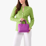 Cattleya Small | Model holding a petite tote purse with structured leather handles and crossbody strap