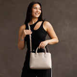 Dragon Bone Large | Model holding mid-size tote purse with  structured leather handles and crossbody strap