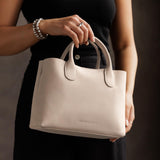 Dragon Bone Large | Model holding mid-size tote purse with  structured leather handles and crossbody strap