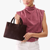 Velvet Brown Large | Model holding mid-size tote purse with  structured leather handles and crossbody strap