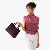 Velvet Brown Large | Model holding mid-size tote purse with  structured leather handles and crossbody strap