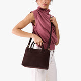 Velvet Brown Large | Model holding mid-size tote purse with  structured leather handles and crossbody strap