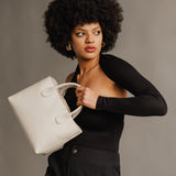 Bone Large | Model holding mid-size tote purse with  structured leather handles and crossbody strap