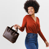 Coldbrew Large | Model holding mid-size tote purse with  structured leather handles and crossbody strap