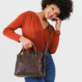 Coldbrew Large | Model holding mid-size tote purse with structured leather handles and crossbody strap